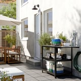 Scène moderne en plein air avec des paniers DJURTRÄNARE sur un support. Paniers en noir/blanc, ronds, pour ranger les articles sur le patio.