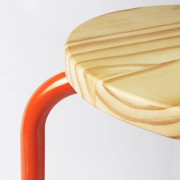Tabouret moderne en métal rouge avec assise en bois clair, bords lisses.