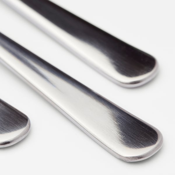 Trois cuillères en acier inoxydable poli disposées soigneusement, réfléchissant la lumière, présentant un design élégant et durable.