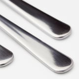Trois cuillères en acier inoxydable poli disposées soigneusement, réfléchissant la lumière, présentant un design élégant et durable.