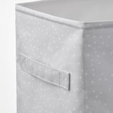 Gros plan de la boîte de rangement en tissu avec poche avant, blanche avec de petits points.