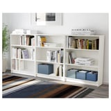 Une étagère blanche avec des livres, plusieurs boîtes en tissu en bleu, un cadre élégant pour la pièce, sert de solution de rangement.