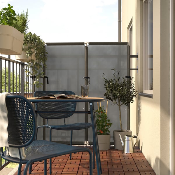 Balcon avec table et chaises bleues DUVSKÄR, plantes, mur blanc.