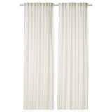 Les rideaux en lin blanc pendent droits, offrant de l’intimité avec un tissu transparent.