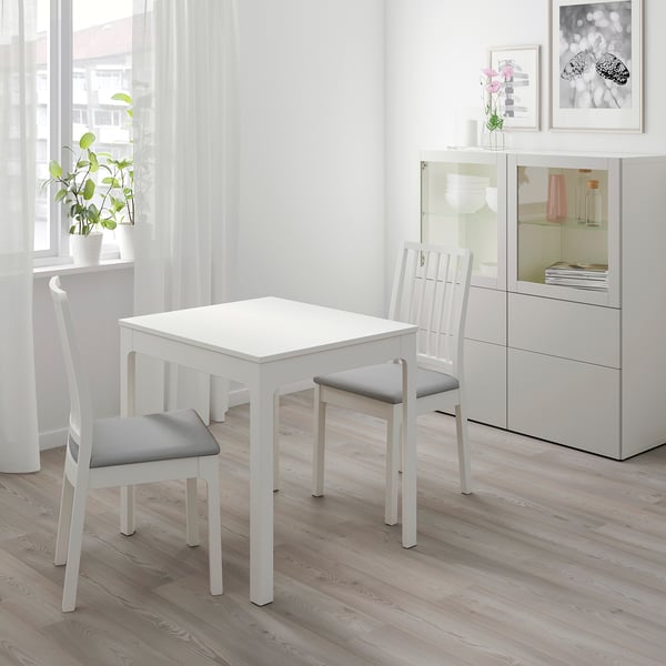 Petit ensemble de salle à manger blanc avec table carrée et deux chaises rembourrées, idéal pour les espaces confortables.