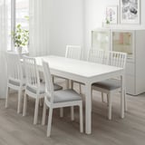 Ensemble de salle à manger extensible blanc moderne avec 4 chaises rembourrées grises dans une pièce lumineuse.