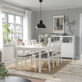 Salle à manger moderne avec table extensible blanche, chaises assorties, tapis, suspension noire et vue sur la ville.