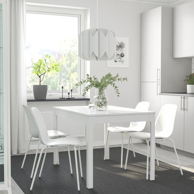 Salle à manger minimaliste moderne avec table extensible EKEDALEN, quatre chaises, vase de verdure et suspension.