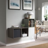 Rangement mural EKET avec des cubes noirs et blancs, du verre et des étagères contenant des livres, des plantes et une lampe. Design moderne et fonctionnel pour les petits espaces.