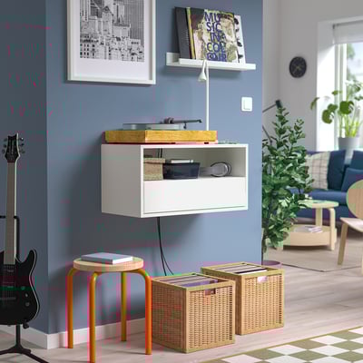 Espace de vie moderne avec étagère murale EKET, tourne-disque, tabourets orange, rangement pour vinyles et guitare.