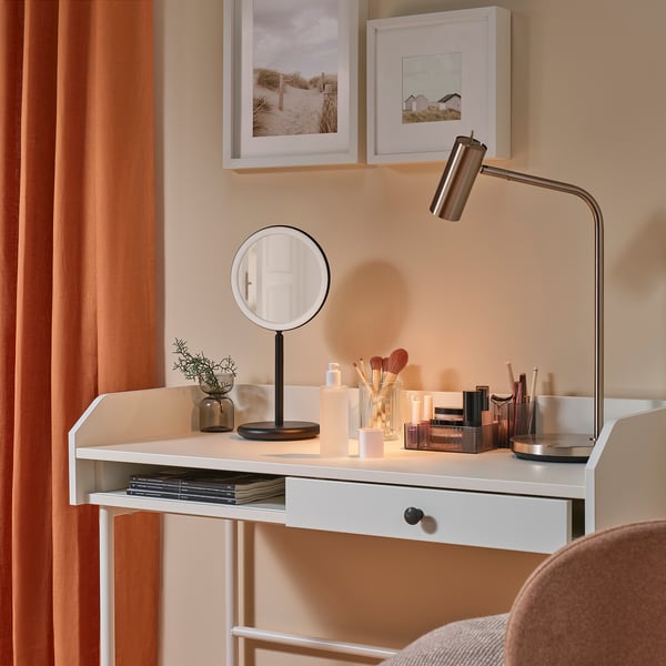 Un bureau de courtoisie moderne avec un miroir grossissant éclairé, du maquillage et de la décoration.