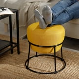 Personne allongée les pieds vers le haut sur un pouf EMMISLÖV jaune vif, mettant en valeur son utilisation comme repose-pieds.