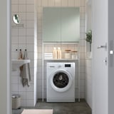 Blanchisserie minimaliste avec étagère ENHET, machine à laver, serviettes organisées, porte gris-vert.