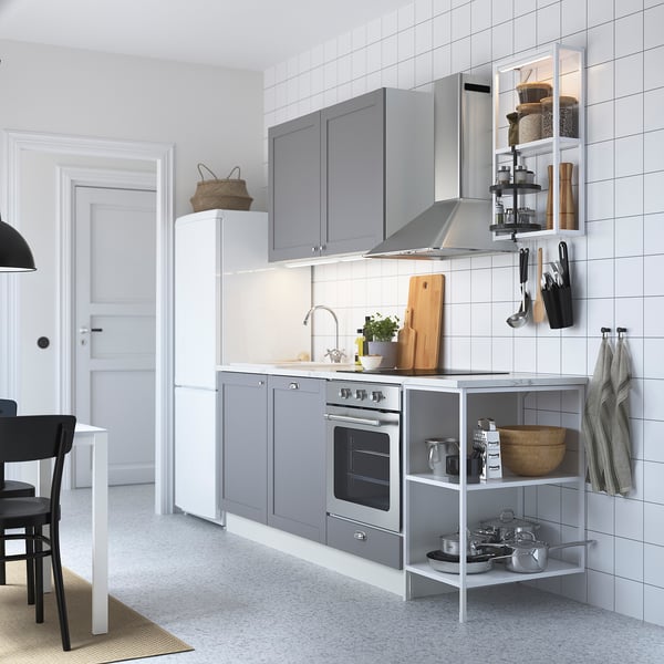Cuisine grise moderne avec dosseret en tuiles blanches, appareils électroménagers en acier inoxydable, ustensiles de suspension et un évier en céramique à cuve unique.