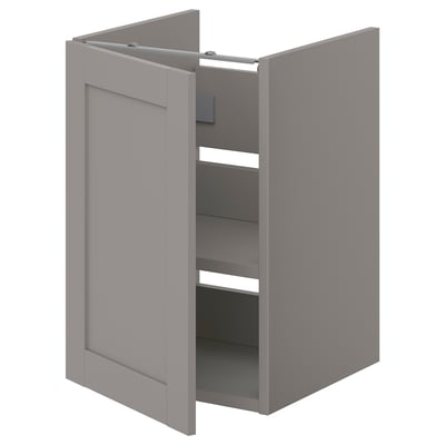 Cette image montre une armoire de salle de bain ENHET grise avec une porte ouverte, révélant des étagères à l’intérieur. L’armoire est rectangulaire avec des surfaces lisses.