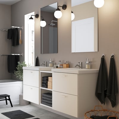 Salle de bain moderne avec vanité blanche ENHET. Lavabos doubles, serviettes noires, plantes et décoration minimaliste.