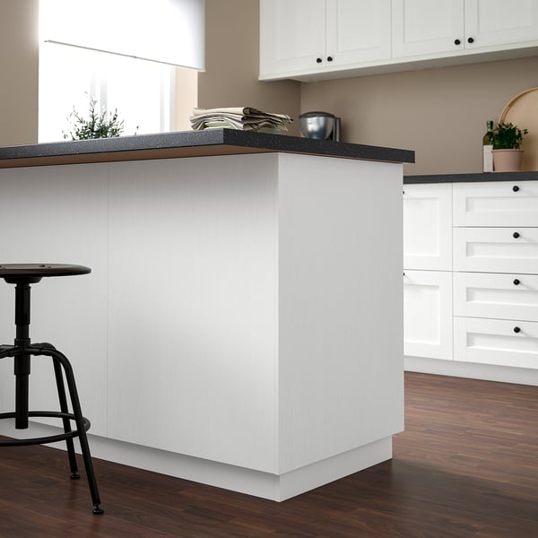 Îlot de cuisine blanc moderne avec comptoir foncé. Entouré de tabourets noirs et de parquet. Les armoires sont ENKÖPING, élégantes et durables.