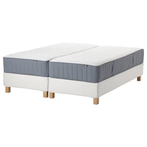 Deux matelas blancs et gris sur un sommier blanc avec des pieds en bois.