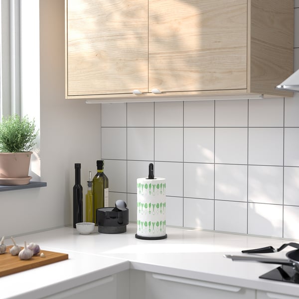 Un comptoir de cuisine avec un porte-rouleau FAMILJ blanc au design de feuilles vertes.