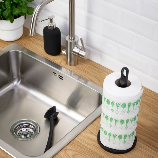 Évier de cuisine avec robinet en acier inoxydable, distributeur de savon et porte-serviettes en papier avec motifs de feuilles vertes.