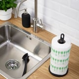 Évier de cuisine avec robinet en acier inoxydable, distributeur de savon et porte-serviettes en papier avec motifs de feuilles vertes.