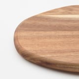 Planche à découper en bois, acacia poli lisse, grain naturel apparent, rond avec des bords incurvés.
