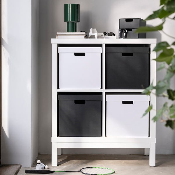 Une boîte en carton FJÄDERHARV blanc sur une étagère kallax, parfaite pour le rangement, s’insérant parfaitement parmi d’autres articles.