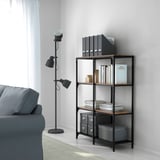 Salon moderne : canapé gris, bibliothèque, lampe orientable.