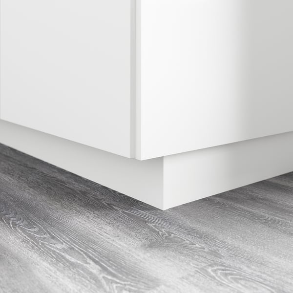 Base d’armoire de cuisine blanche avec socle, couvrant l’espace entre le sol et l’armoire.
