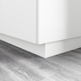 Base d’armoire de cuisine blanche avec socle, couvrant l’espace entre le sol et l’armoire.