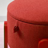 Siège rembourré rouge avec coutures épaisses, montrant un tissu doux et de haute qualité.