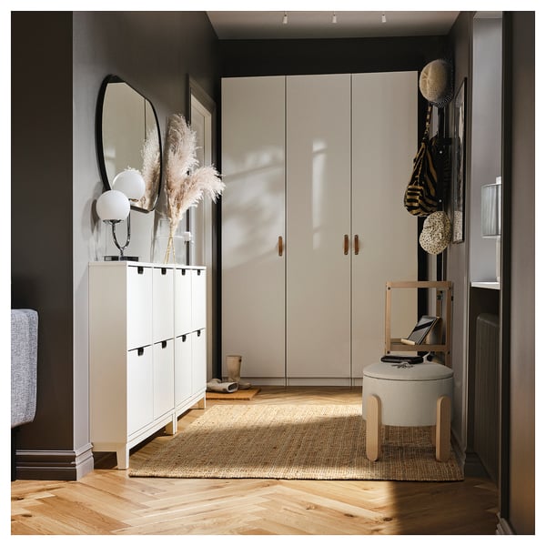 Entrée moderne avec rangement, miroir, plantes, planchers de bois, tabouret et tapis.
