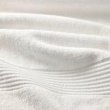 Serviettes blanches douces avec un motif tissé complexe, mettant en valeur un savoir-faire de haute qualité et une texture moelleuse.