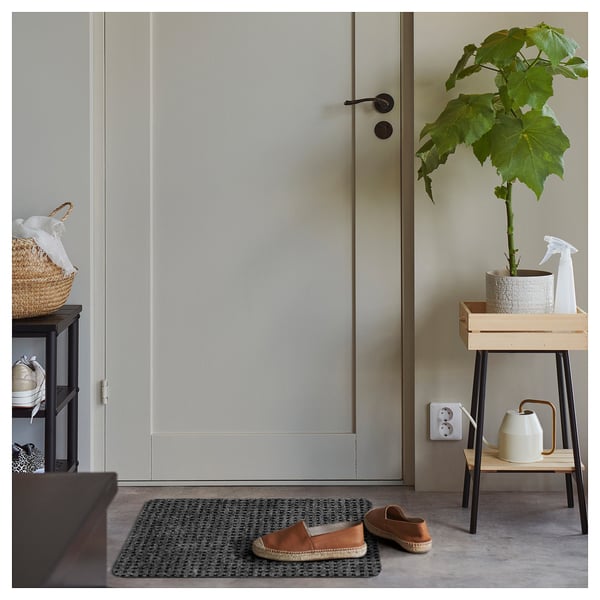 Tapis FRIKTION gris attrape la saleté, banc avec plante et arrosoir.