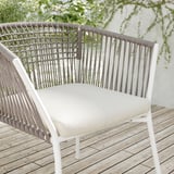 Chaise de patio blanche moderne avec dossier tressé, coussin beige.