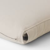 Gros plan d’une housse de coussin d’extérieur beige avec fermeture éclair et sangle élastique, mettant en valeur un tissu de qualité.