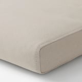 Gros plan d’une housse de coussin d’extérieur beige et texturée avec une fermeture éclair, fabriquée à partir de matériaux recyclés.