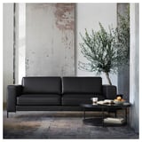 Salon moderne : canapé gris, table basse noire, olivier, décor industriel.