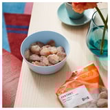 Bonbons gélifiés dans un bol à côté de FYRTAKT cola, gelées aigres et vase bleu avec fleur.