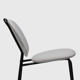 Chaise moderne avec assise et dossier en tissu gris clair, pieds en métal noir, angle confortable.
