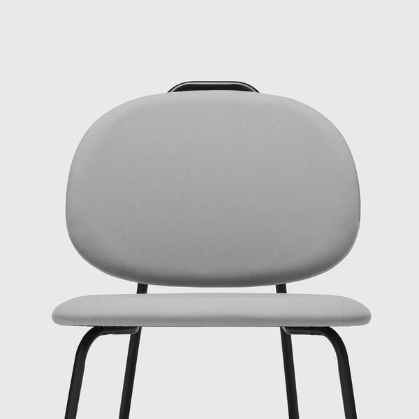 Fauteuil moderne avec un tissu gris clair, un design incurvé, des pieds noirs robustes et un angle d’assise confortable.
