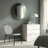 Chambre moderne avec fauteuil GÄVLE, coffre, miroir et lit.