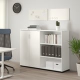 Unité de rangement de bureau GALANT blanche avec étagères ouvertes/fermées pour ranger les classeurs, les livres et les boîtes, à côté d’une chaise et d’un bureau bleus dans un espace de travail moderne.