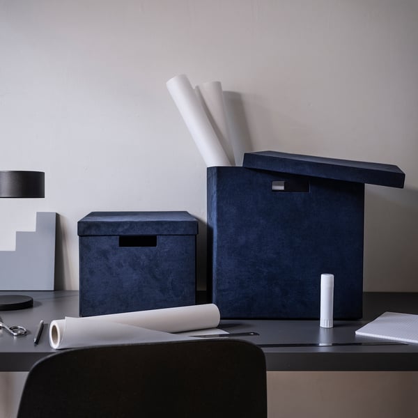 Configuration de bureau moderne avec des boîtes de rangement en velours bleu GJÄTTA, des moments en taille à côté du papier A4 et des blocs-notes pour l’échelle. Décoratif et fonctionnel.