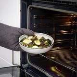 Personne plaçant le plat cuit dans le four. Produit : Plat à four GLADELIG.