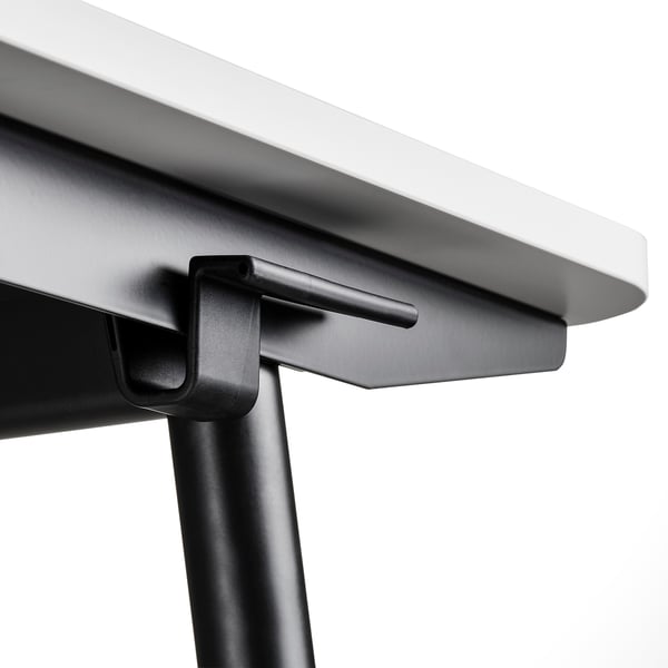 Gros plan du bord d’un bureau assis-debout moderne, présentant un design élégant et des matériaux de qualité.