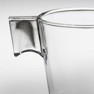 Pichet en verre transparent avec une poignée robuste, mettant en valeur la qualité et la clarté