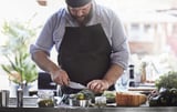 Un chef barbu hache des légumes dans la cuisine.