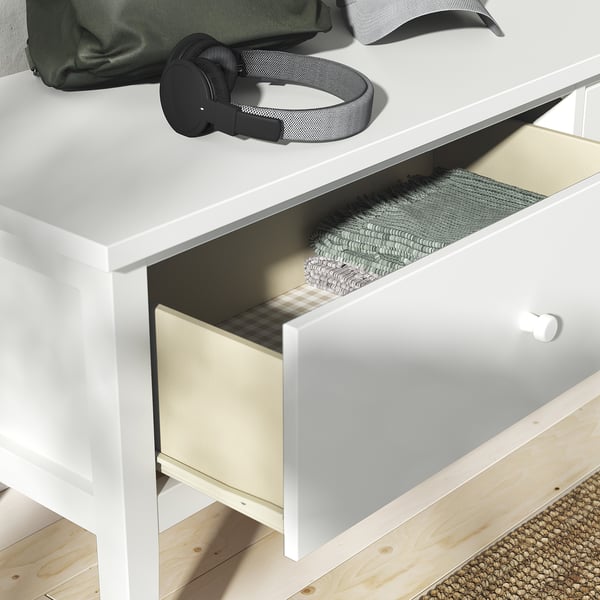 Commode GULLABERG blanche avec tiroir ouvert laissant apparaître les vêtements pliés. Casque et sac sur le dessus.