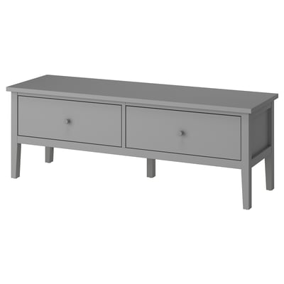 Cette image est un banc de rangement GULLABERG gris, avec deux tiroirs spacieux et des poignées en bois, conçu dans un style traditionnel pour une utilisation dans le couloir ou la chambre à coucher.